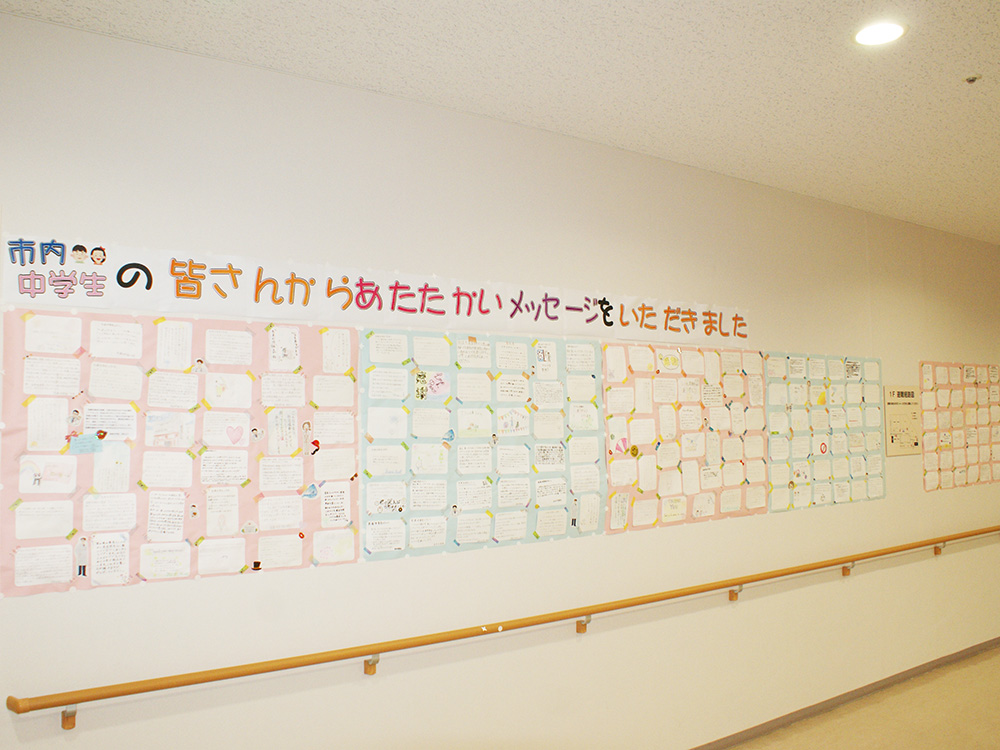 「市内中学生の皆さんからあたたかいメッセージをいただきました」の文字の下に模造紙に付けられた沢山のメッセージが壁一面に飾られている写真