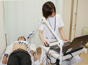 看護師の方が男性の胸部に装置を付け心電図を測定している写真