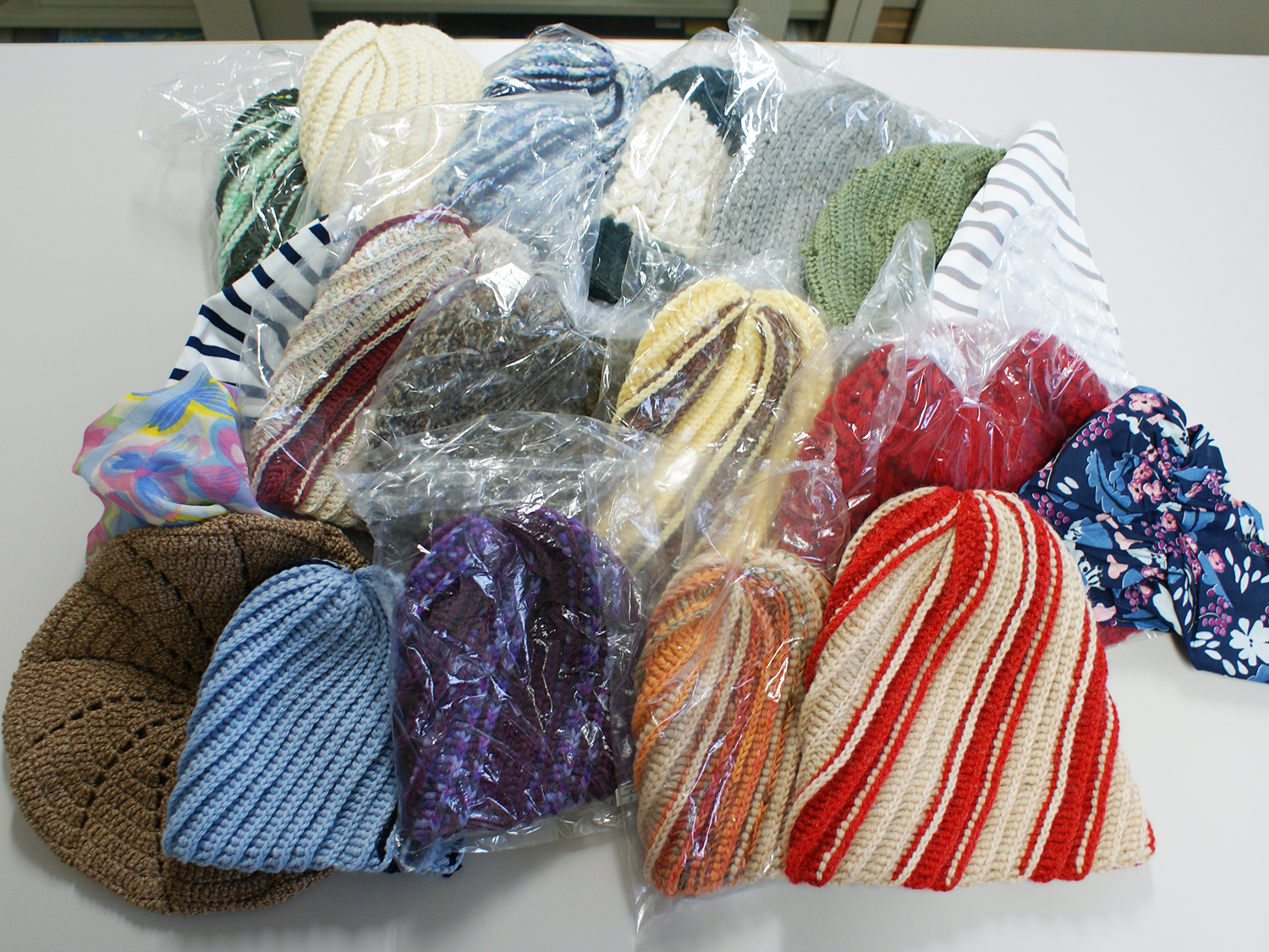 大小様々な大きさで、カラフルな色の沢山の手編みのケア帽子の写真