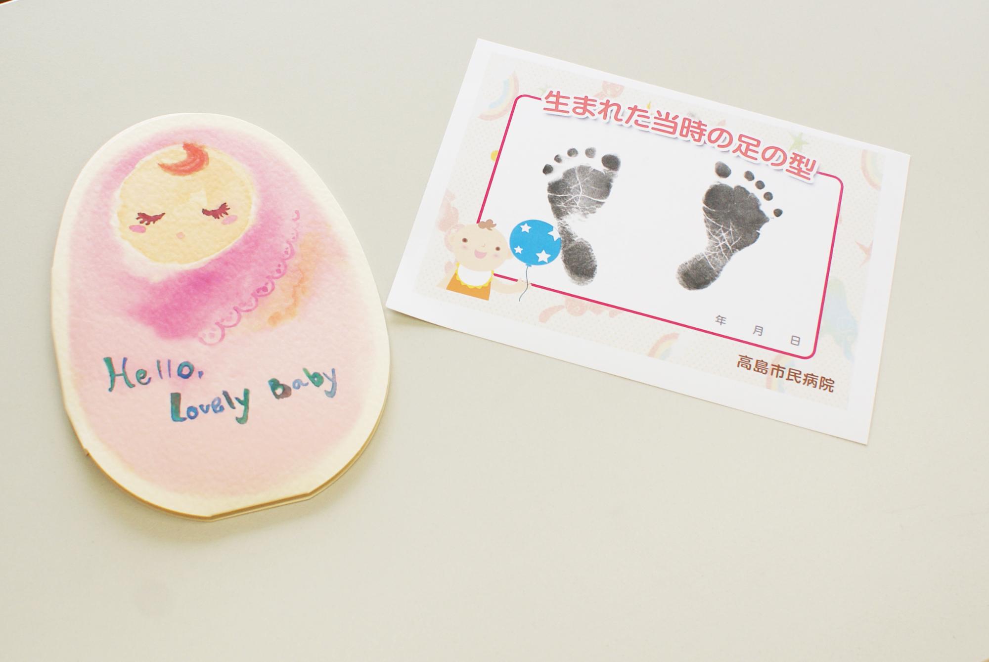 赤ちゃんのイラストが描かれたボイスカードと、赤ちゃんの足型が写された用紙の写真