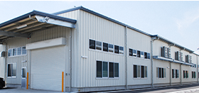 屋根が高く奥に長い白色の壁の紺藤織物株式会社の工場の写真
