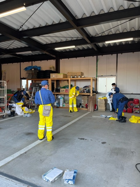 消防団の車庫内で黄色の雨具を着ている消防団員の写真