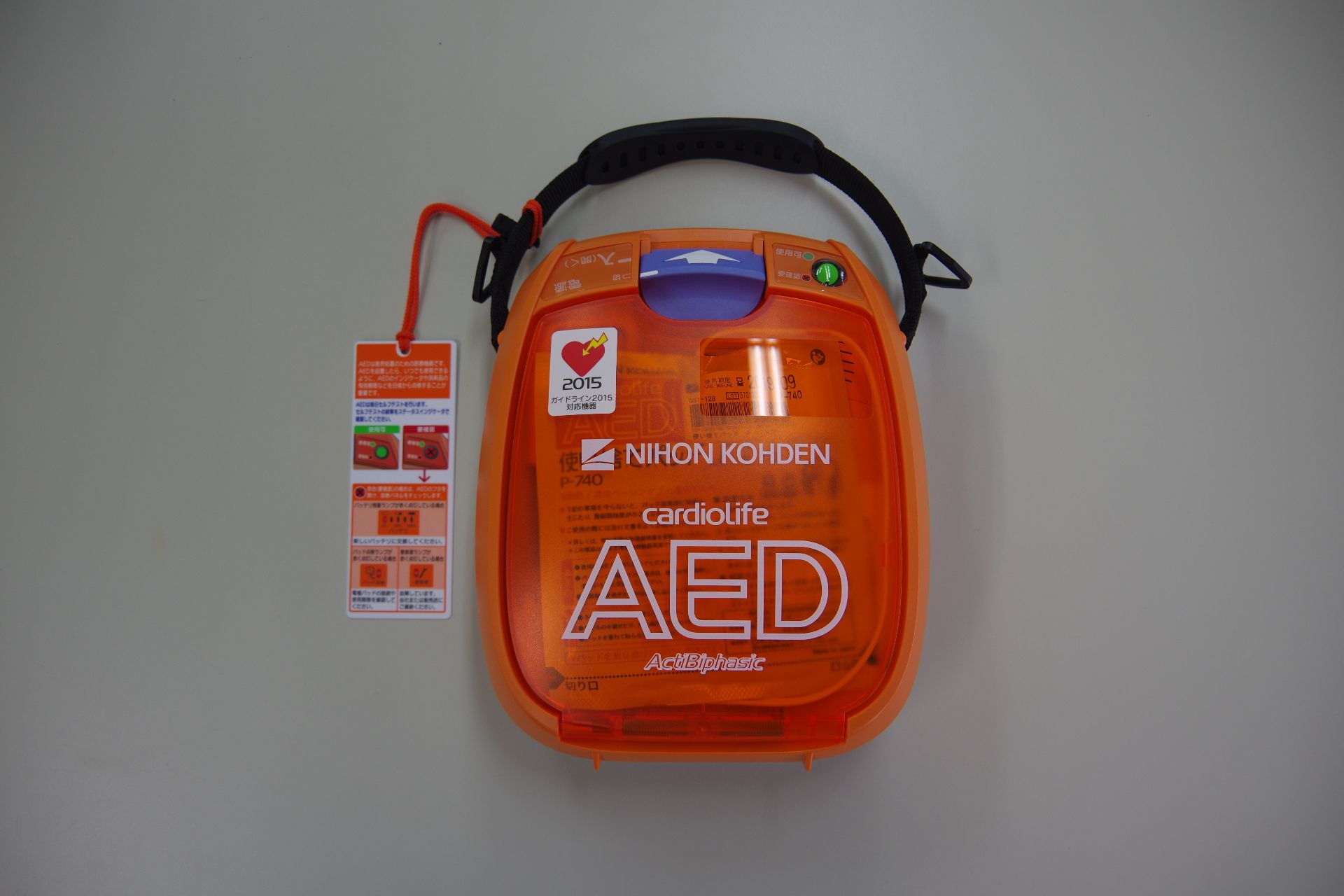 半透明なオレンジ色のケースの中に電極パッドや液晶が入っているAEDの写真