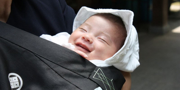 抱っこされて笑顔を浮かべる赤ちゃんの写真
