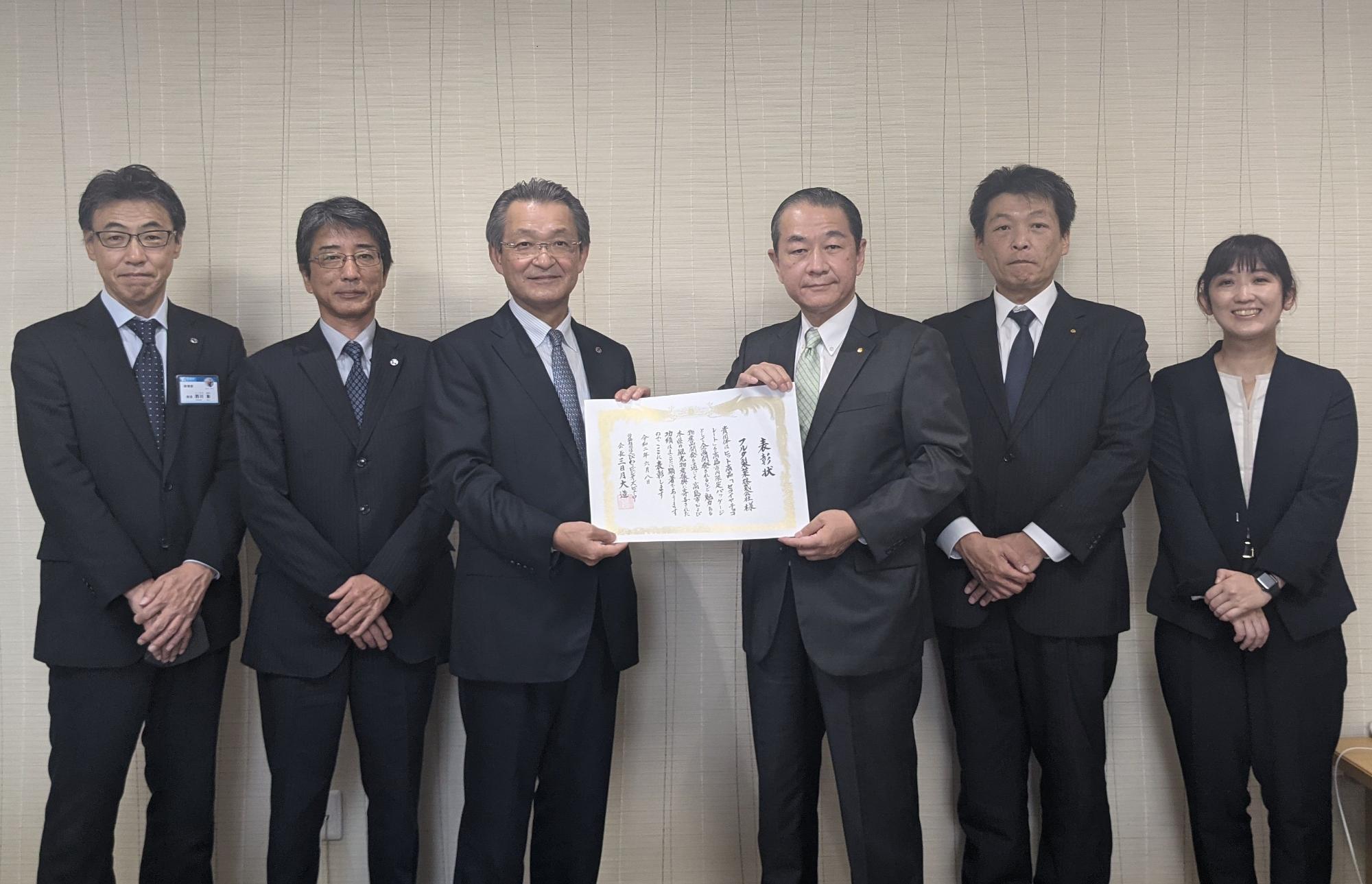 左右に二人ずつ関係者が立ち、中央で福井市長と古田社長が表彰状を持っている表彰状伝達式の写真