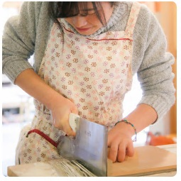 大剣取材に訪れた女子高生が作ったそば生地を麺切包丁で慎重に切っている様子の写真