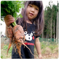 収穫したての大きなニンジンを持っている女の子の写真