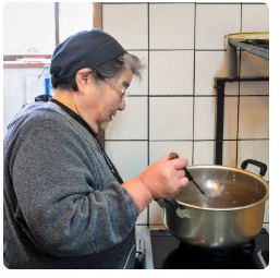 ぜんざいの入った鍋をかき混ぜる女性の写真