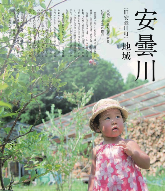 葉ながらのワンピースを着て麦わら帽子をかぶった女の子がブルーベリーがなっている木の横に立っている写真