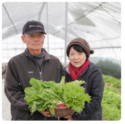 かごに入った収穫した野菜を2人で持っている高城さんご夫婦の写真