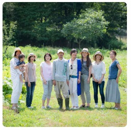 松原さんの畑で中央に松原さん、中川さんが立ち左右に3人ずつ女性が立っている集合写真