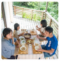 広いテラスにテーブルを置き四人で食事をしている馬込さん一家を上から撮影した写真