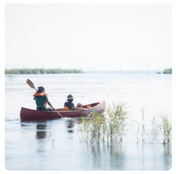 親子3人で湖に浮かぶカヌーに乗り、崇さんがオールでカヌーを漕いでいる写真