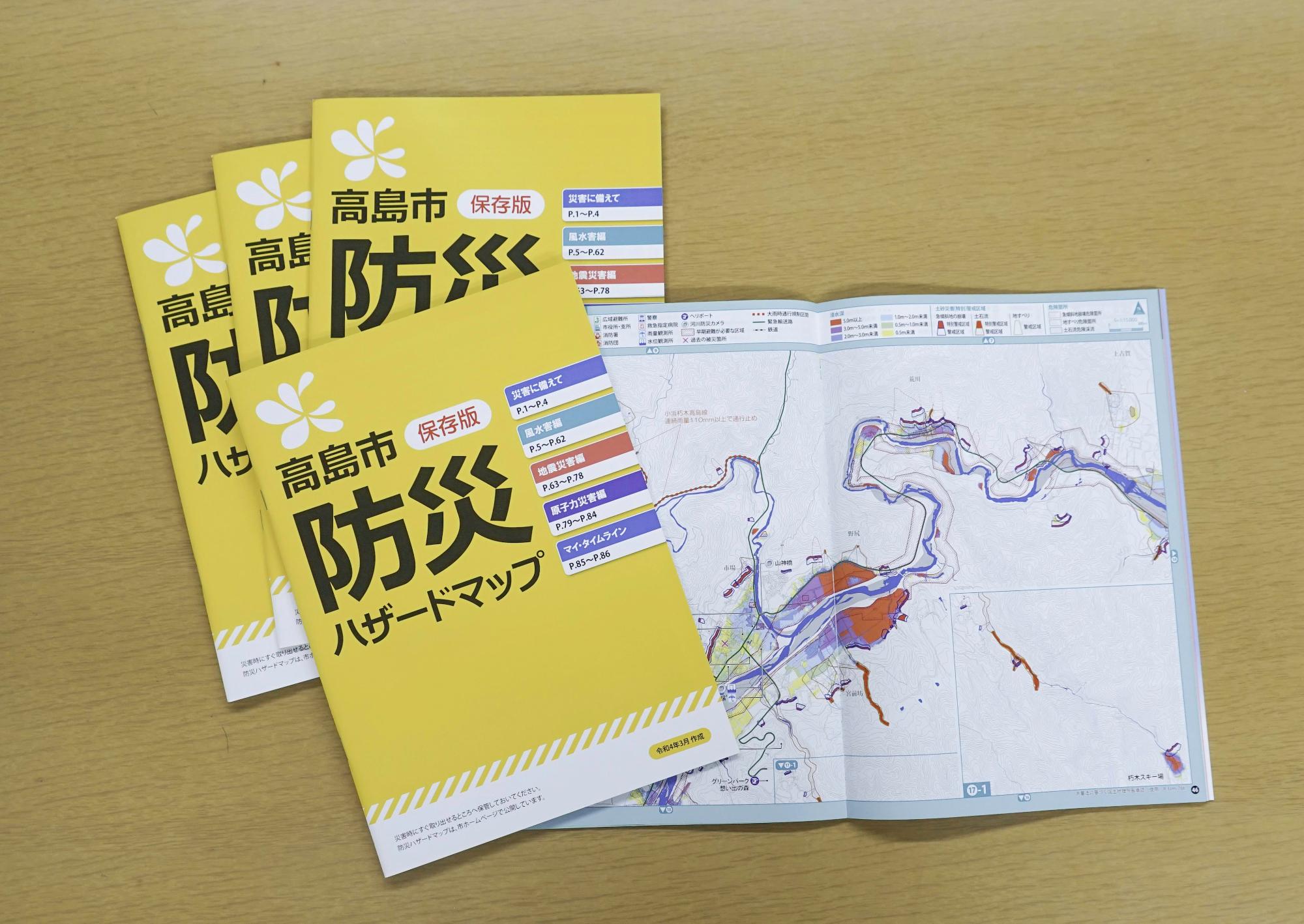 高島市防災ハザードマップ4冊と、ページが開いた状態のハザードマップ1冊の写真