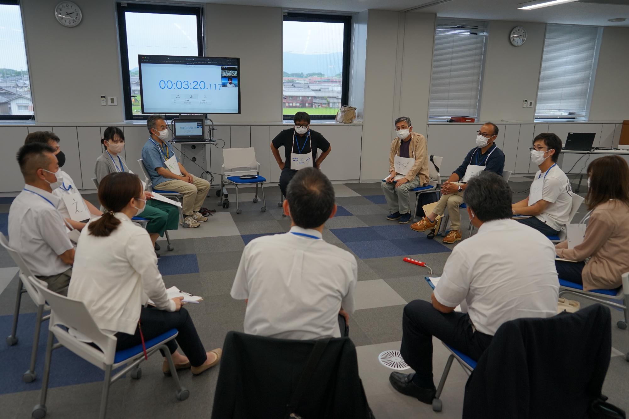 会議室で円形に椅子に座り、話し合いをしている参加者の写真