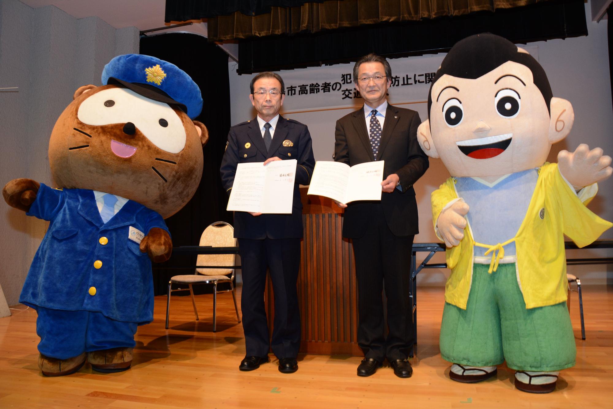 けいたくんとよえもん君の間に市長と高島警察署の代表者が立ち、協定書を持っている写真