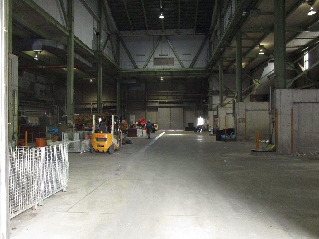 左側はフォークリフトや資材などが置かれ、右側に区分けされたごみ置き場がある環境センター場内の写真