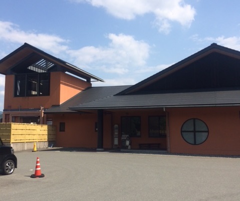 黒い三角屋根にオレンジ色の外壁で、入口付近に丸い窓があるマキノ白谷温泉八王子荘の写真