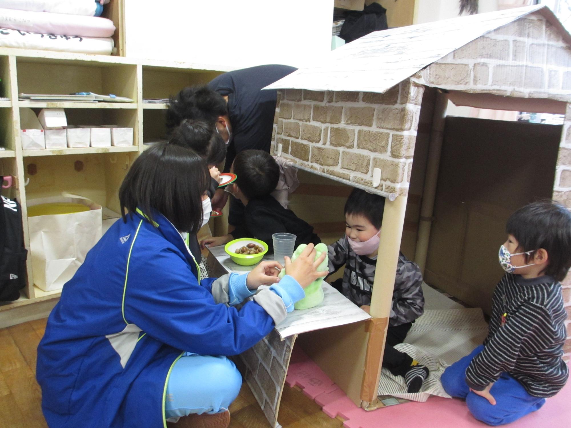 小さな家に入った園児と遊ぶマキノ中学校の生徒の保育実習の様子の写真