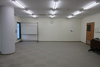入口側の壁に折り畳み机、正面の壁際にホワイトボードが置かれている会議室3-Aの写真