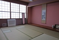 奥に格子状の窓があり、淡いピンク色の壁に水墨画が描かれた掛け軸が飾られている和室の会議室3－Cの写真