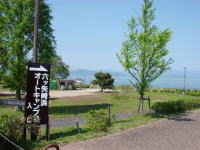 大きな広場の手前にオートキャンプ場入口と書かれた看板が置かれている六ツ矢崎浜園地の写真