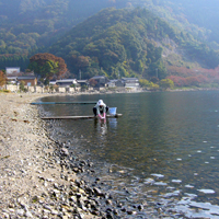 琵琶湖の砂浜が続く奥に住宅街や山が見える「高島市マキノ町」の写真