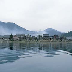 向こう岸に集落や山々が見えるマキノ町の湖を水面の近くから撮影した写真