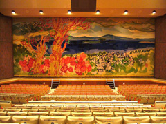 高台から市街地から琵琶湖、山並みまでを見下ろした絵画が描かれた舞台幕が設置されたホールの写真