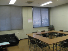 左側にソファ席、右側に2脚ずつパイプ椅子がセットされたロの字に設置した長机が並んでいる練習室2の写真