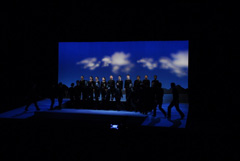 全身黒色の服を着た人たちがステージの中央に集まってきているシーンの写真