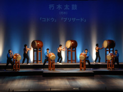 3つの大きな太鼓と4つの中くらいの大きさの太鼓を叩いている演奏の様子の写真