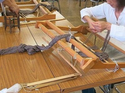 女性が染めた糸をハタ織り機を使って織っている様子の写真