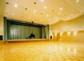 天井が波状になっていて舞台にピアノが設置された、ふじのきホールの写真