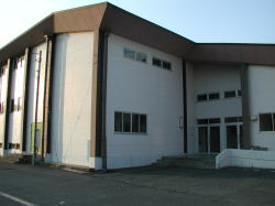 白と茶色を基調とした建物で、正面に駐車スペースがある今津上体育館の外観写真